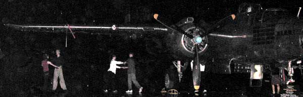 Couples dance under a bomber's wing.