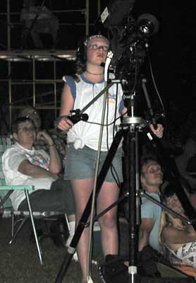 Heather stands behind the tripod-mounted video camera.