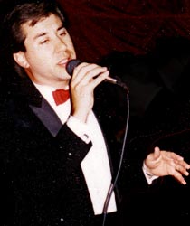 Keith holds the mic and gestures with his left hand.