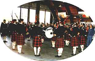 Dressed in kilts and other traditional garb, the pipers and drummers stand in a circle to play inside the hangar.