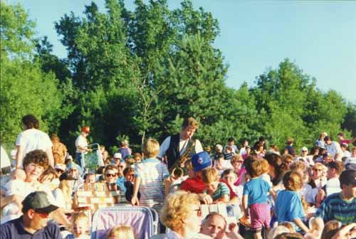 Brian plays a tenor sax solo, surrounded by adults and children who have gathered for the July 4th, 1993, festivities in Roseville's Central Park.