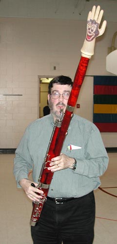 Glen plays the bassoon, standing. An inflated glove with Mickey Mouse's face extends out of the bassoon's bell.