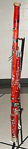 The bassoon sits on a bass clarinet stand. Most of the glove is stuffed inside the bell, but part is visible.