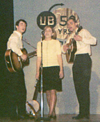 Glen, Carmen, and Mike sing on stage.