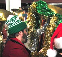 Glen Newton plays a decorated tuba, wearing a knit "TUBA CHRISTMAS" hat.