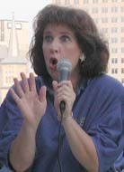 Karen gestures with her right hand while holding the mic with her left.
