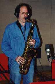Dressed in blue, Glen plays tenor sax with headphones on.